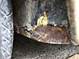 Rust at lower rear of left front wheel well